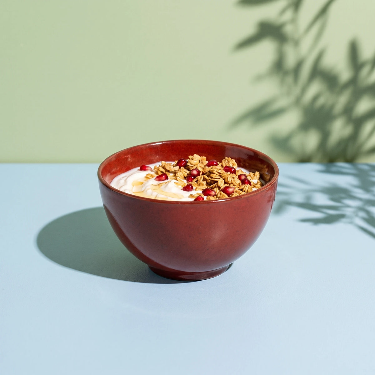 Dem Kırmızı stoneware çorba kasesinde süzme yoğurt, granola ve nar